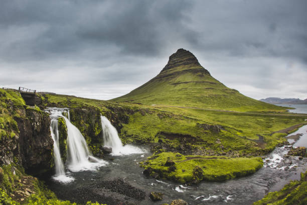 kirkjufellsfoss wasserfall und kirkjufell berg dahinter. an sehr bewölkten und regnerischen tag in island. schöne landschaft - snaefellsnes stock-fotos und bilder