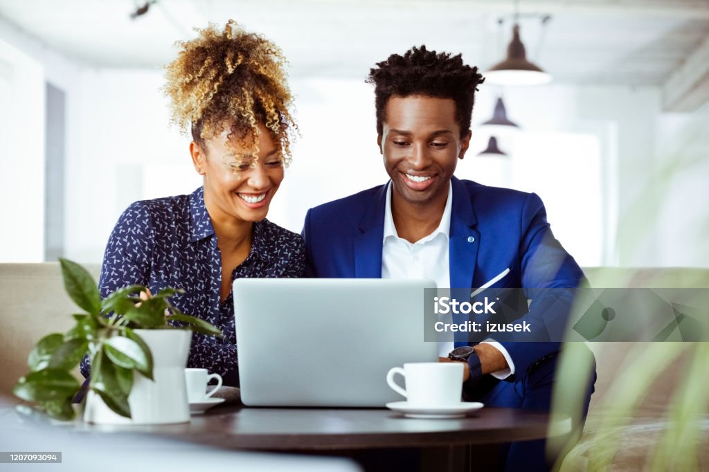 Confident entrepreneurs working on investment plan Confident entrepreneurs working on investment plans at work place. Financial experts are smiling while using laptop. They are working in team. 30-34 Years Stock Photo