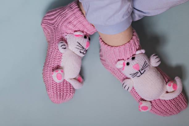 nogi dziewczyny w zabawnych różowych skarpetkach z kotami na niebieskim tle. przytulne kapcie do domu. - fuzzy pink slippers zdjęcia i obrazy z banku zdjęć