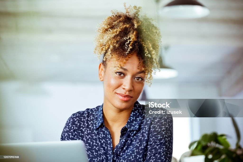 Portrait of smiling mid adult businesswoman Portrait of smiling mid adult businesswoman. Confident financial advisor is working in office. She is having highlighted curly hair. 30-34 Years Stock Photo
