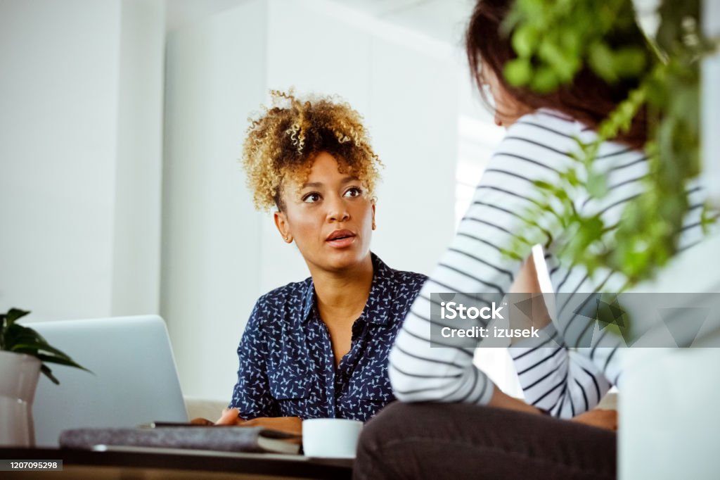 Serious financial advisor looking at woman Serious female financial advisor looking at customer. Woman and corporate professional are having meeting in office. They are discussing related finance. Serious Stock Photo