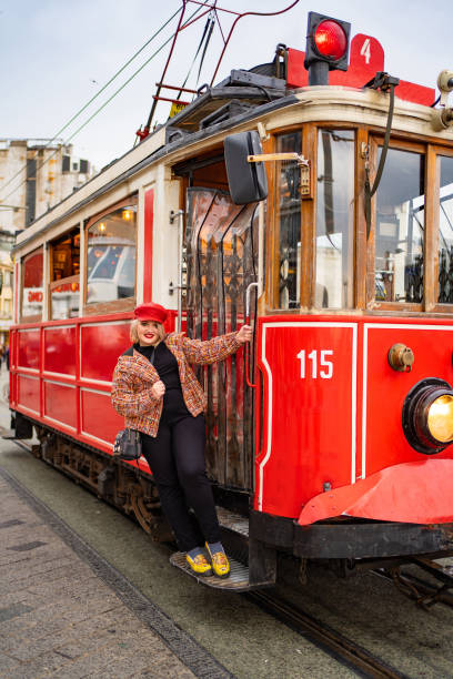 istock blond girl in jacket stand running Board red tram 1207095529