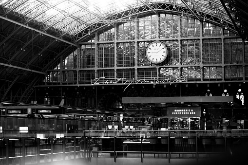 January 28, 2020 - London, UK: St Pancras Railroad Station interior - large glass ceiling and walls, railing, cafe, wall clock - b7w photo