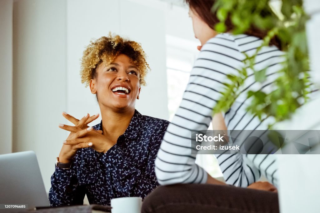 Woman visiting cheerful financial expert in office Woman visiting cheerful financial expert in office. Businesswoman and customer are planning finance. They are in meeting. Casual Clothing Stock Photo