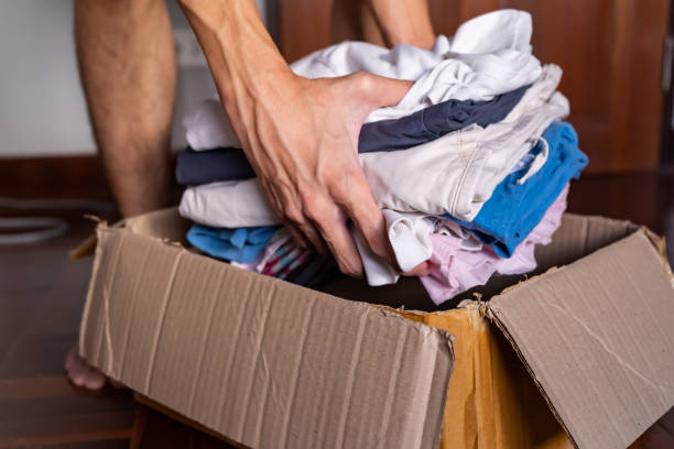 Putting clothes into a cardboard box for donation Putting clothes into a cardboard box for donation clothing donation stock pictures, royalty-free photos & images