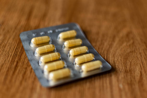 Yellow, oval-shaped tablets in capsules, absorbable shell with powder inside stock photo
