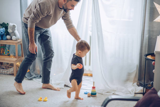 Practice to walk Young father helping baby to practice walking, they are home and enjoy in time they spending together Barefoot stock pictures, royalty-free photos & images