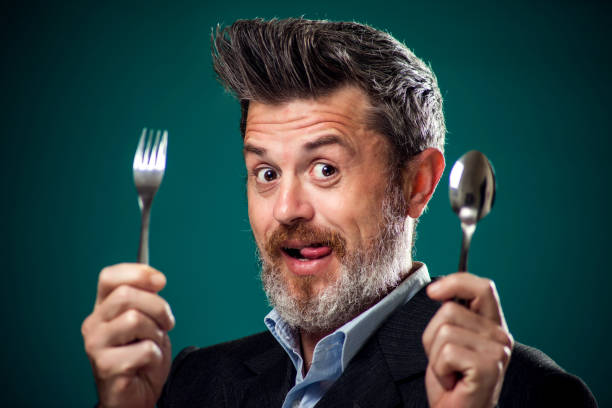 un retrato de hombre hambriento en traje sosteniendo cuchara y tenedor. - dinner currency table business fotografías e imágenes de stock