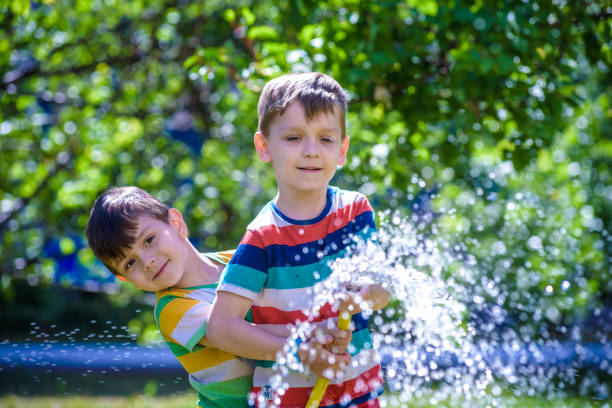 istock Brothers having fun splash each other with water in the village 1207106534