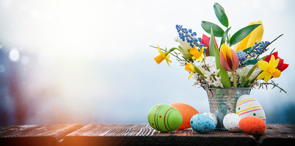 Easter Eggs and Spring Flowers in a Small Metal Bucket on Old Wooden Table