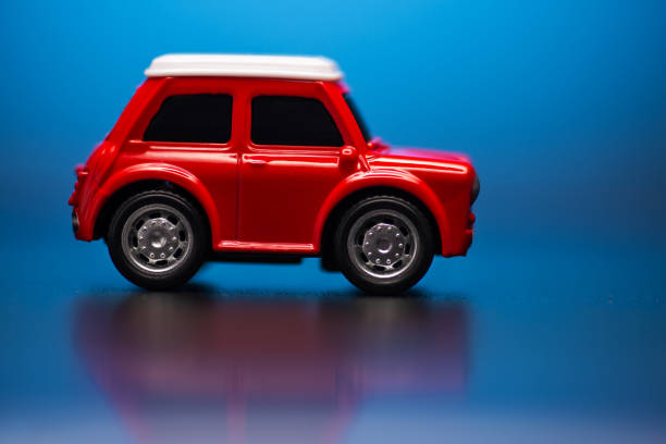 istock Side side; view of Red colored little toy model car on a blue background. 1207109571