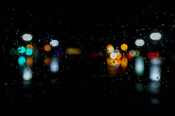 Wet the window with night rain and town lights night city background