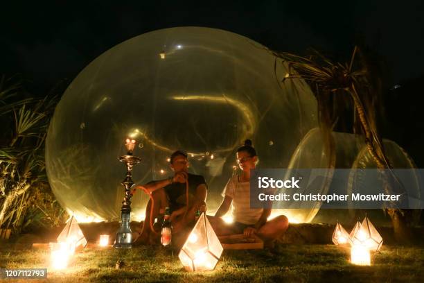 Badung A Couple Sitting In Front Of A Bubble Hotel Stock Photo - Download Image Now