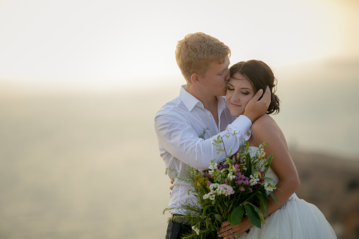 Wedding story of a man and a woman newlyweds on a mountain top against a misty horizon.