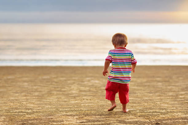istock Child playing on ocean beach. Kid at sunset sea. 1207114163