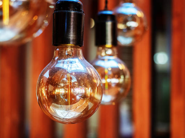 istock Close-up photo of hanging light bulbs with interior reflected in them 1207114337