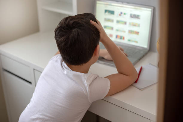 istock The boy sits with his back behind a laptop, looks on the Internet 1207115173
