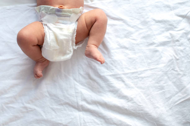 istock Baby legs and bottom in diaper on white bed background, top view, copy space 1207115495