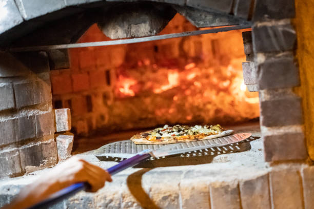 istock Cook baking pizza in a wood fire Brick oven 1207115544