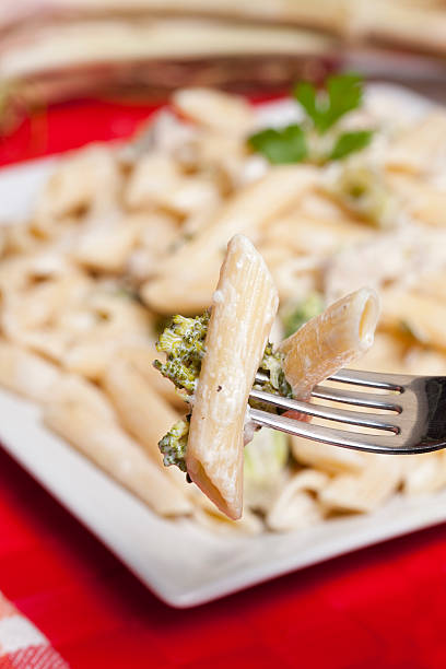 Penne with chicken and broccoli A fork lifting up a mouthful of penne with broccoli and chicken chicken rigatoni stock pictures, royalty-free photos & images