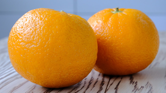 Two tangerines on a wooden surface side view