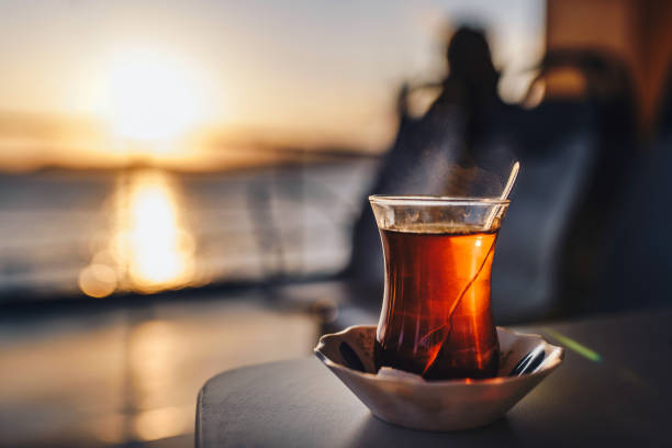 Hot black turkish tea on a table. Turkish tea against the setting sun and the sea. Turkish ferry. stock photo