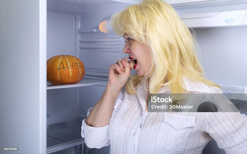 Woman and diet Woman looks at a pumpkin in a refrigerator Adult Stock Photo