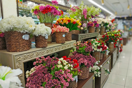Artificial flowers are sold in the store. In baskets are bouquets of various artificial flowers for sale. Artificial flowers to decorate the interior.