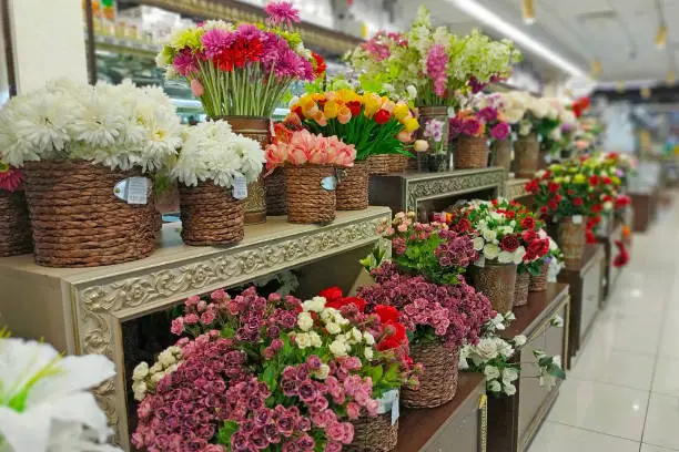 Photo of Artificial flowers are sold in the store. In baskets are bouquets of various artificial flowers for sale