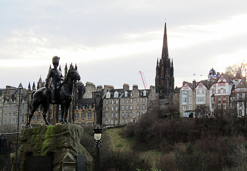 Edinburgh, UK - December 29, 2019: Picture of Edinburgh Castle from far away. An equestrian statue can also be observed at the right. Picture was taken at 100 Princes St. Royal Scots Greys Memorial in Edinburgh.