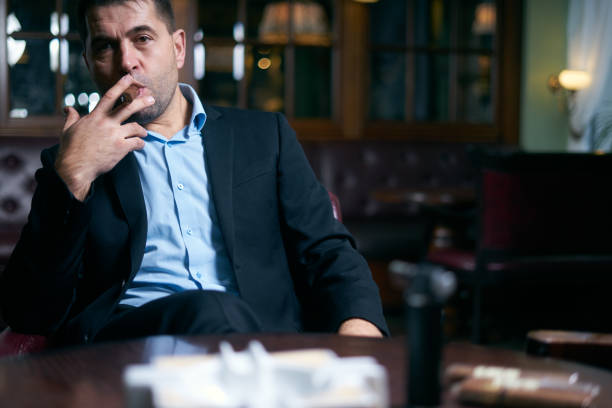 istock Handsome businessman starting smoking cigar in a bar 1207123071