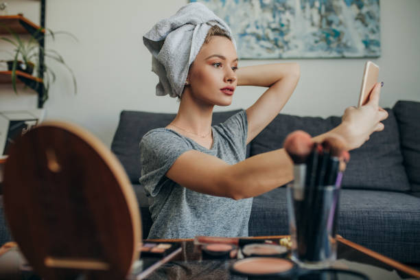 Young woman in her apartment creating a make up selfie Young social media influencer filming her make up routine influencer photos stock pictures, royalty-free photos & images