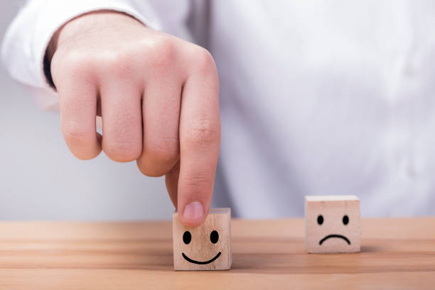 istock Close up hand choose smiley face and blurred sad face icon on wood cube 1207126888