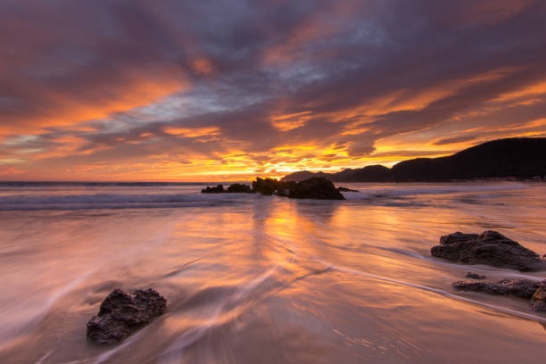 Sunset reflections over the sea at Black Rock Sands near Porthmadog, Caernarfonshire, Wales, UK