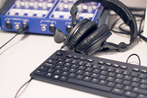 istock Studio time. Close-up headphones  with other professional audio studio equipments. Microphone for podcasts and studio headphones on a PC keyboard on a black background, horizontal frame stock photo. 1207130286