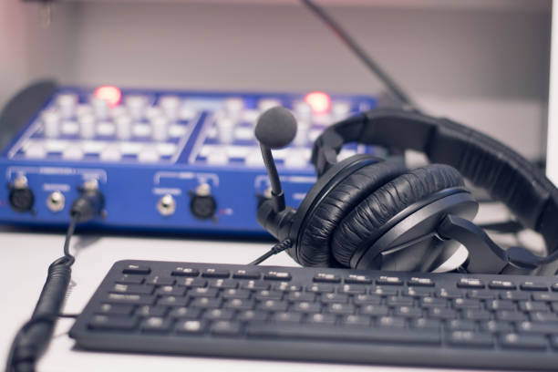 istock Studio time. Close-up headphones  with other professional audio studio equipments. Microphone for podcasts and studio headphones on a PC keyboard on a black background, horizontal frame stock photo. 1207130391