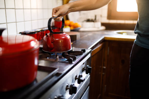 Man putting a kettle on the stove at kitchen