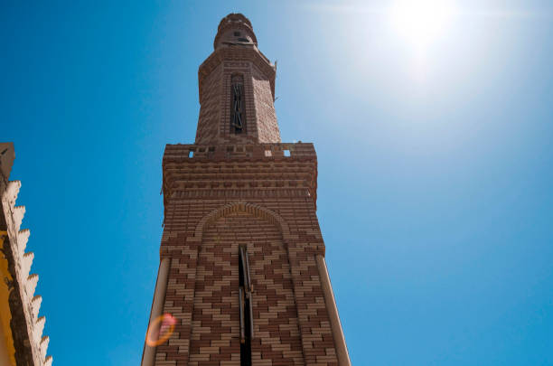 Islamic church tower in blue sky and sun shine in Ramadan day.East culture pray minaret building part.Muslim religion