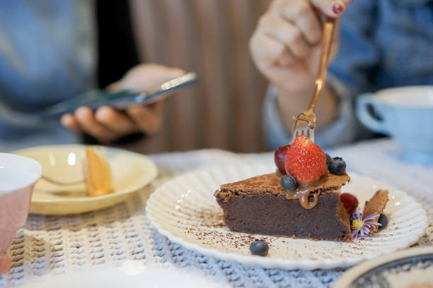 istock close up chocolate cake with strawberry and grape decorated on plate and woman using fork to try to eating with friend in afternoon tea time for people lifestyle concept 1207136550