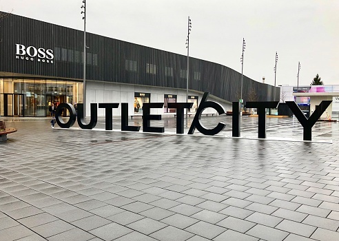 Outletcity / Outlet City  in Metzingen : lot of luxury brand shops with price reduction. On this picture, the shopping mall name written with big letters, and Boss shop in background. February 17, 2020 in Germany