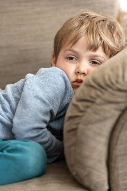 istock Serious Child boy lying in a couch looking away 1207139643