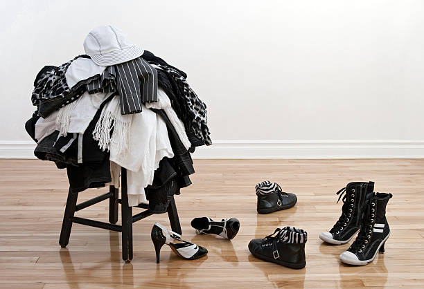 Heap of clothing on a stool and disordered shoes stock photo