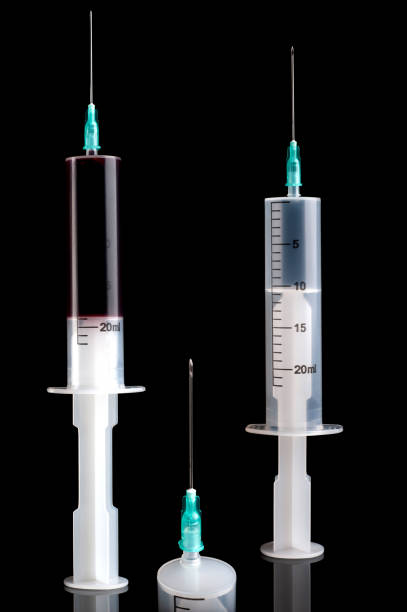 istock a plastic syringe with blood typed on a black background, copy space 1207144216