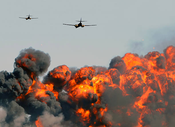 Two planes flying over a big exploding fire with dark smoke Heavy bombers attacking ground targets bomb photos stock pictures, royalty-free photos & images