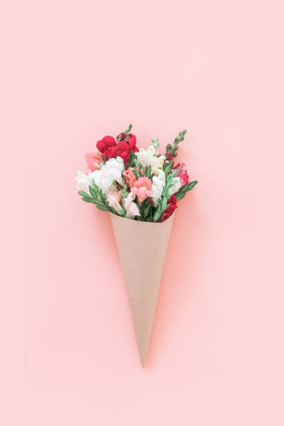 istock Roses bouquet in cone on pink background, flat lay, top view. 1207151225