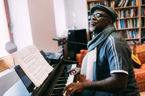 Photo of Senior musician playing the piano at home, relaxing