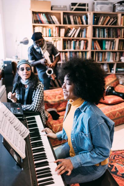 istock Female singer playing the piano with a group in studio 1207153194