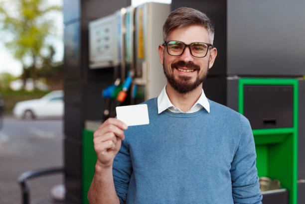 istock Cheerful man with blank card on gas station 1207153523