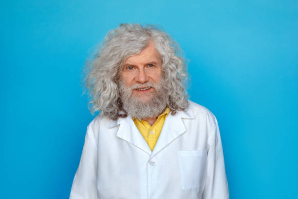 istock Old man wearing doctor's gown studio isolated on blue standing looking camera cheerful 1207153800