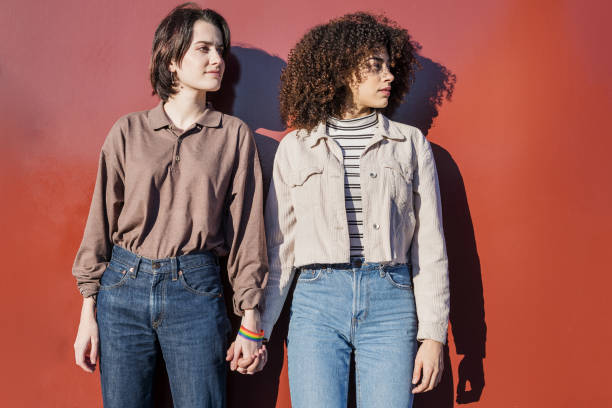 istock lesbian couple holding hands in red background 1207154094